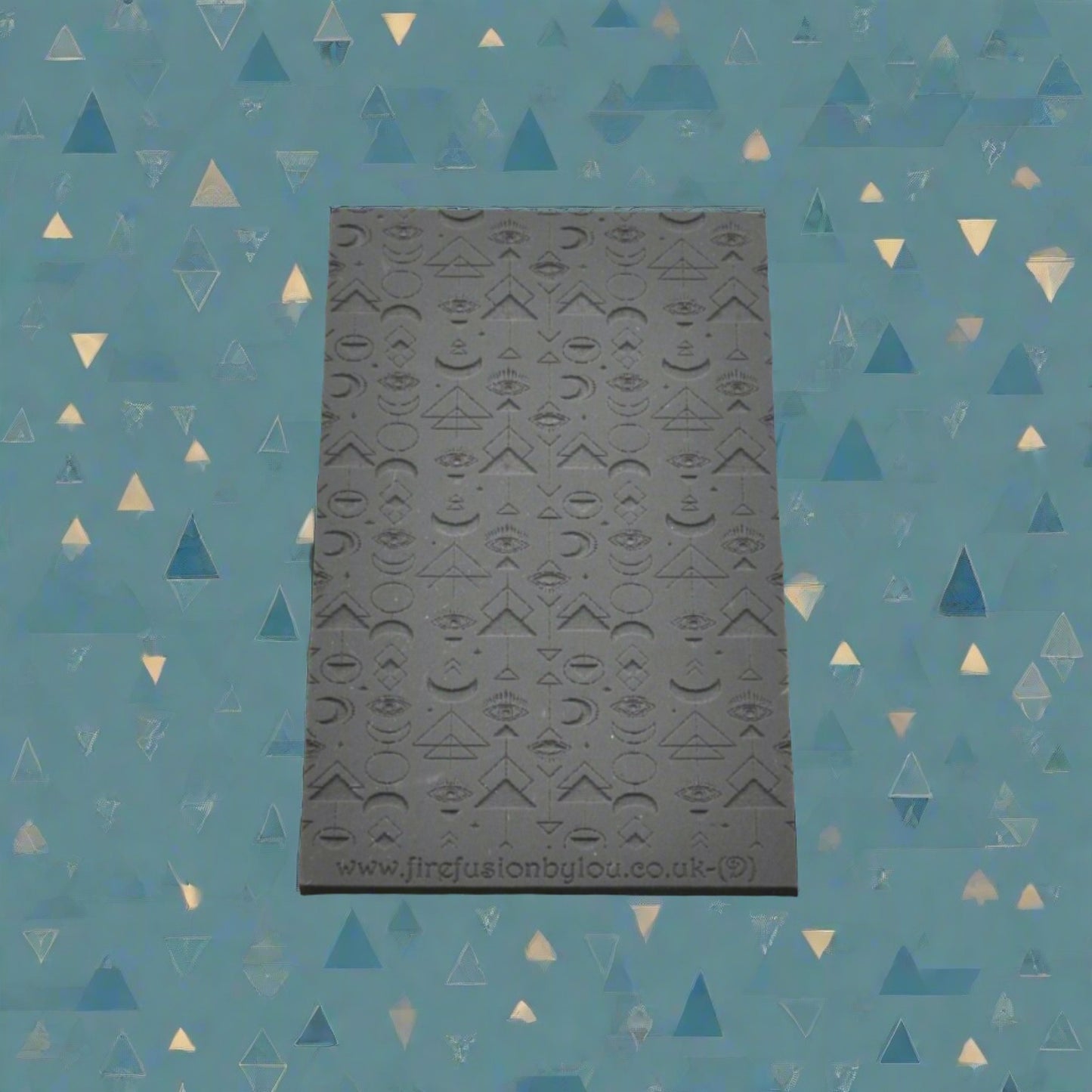 A geometric pattern repeat with mystical eyes debossed texture mat in grey material. For use on metal clay or polymer clay.