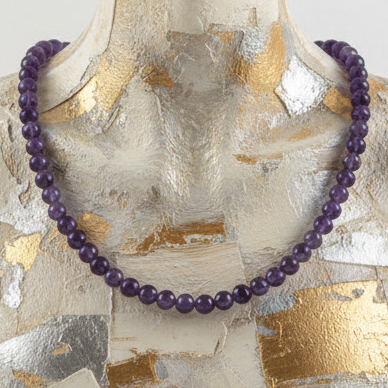 Purple beaded necklace on a textured gold and silver background