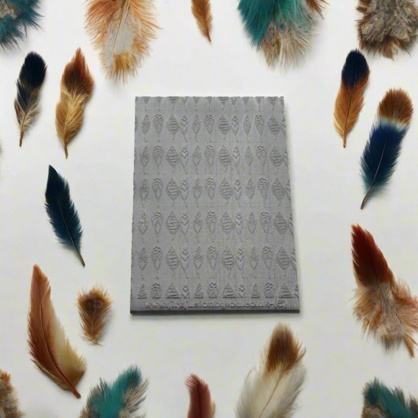 A feather pattern embossed texture mat in grey material. This texture mat will give you an embossed effect on metal clay or polymer clay.