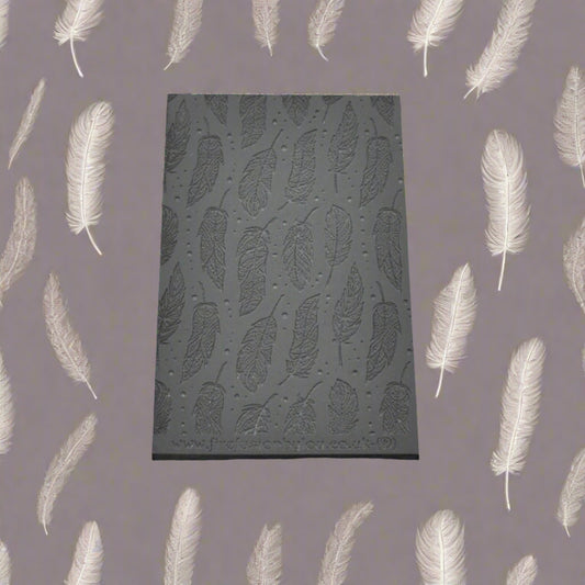 A feather pattern debossed texture mat in grey material. This texture mat will give you an embossed effect on metal clay or polymer clay.