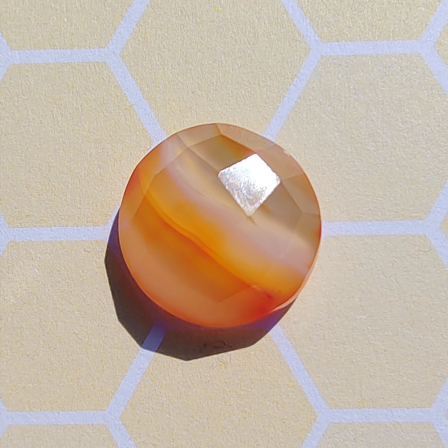 Round orange-brown stone on a beige surface with hexagonal pattern