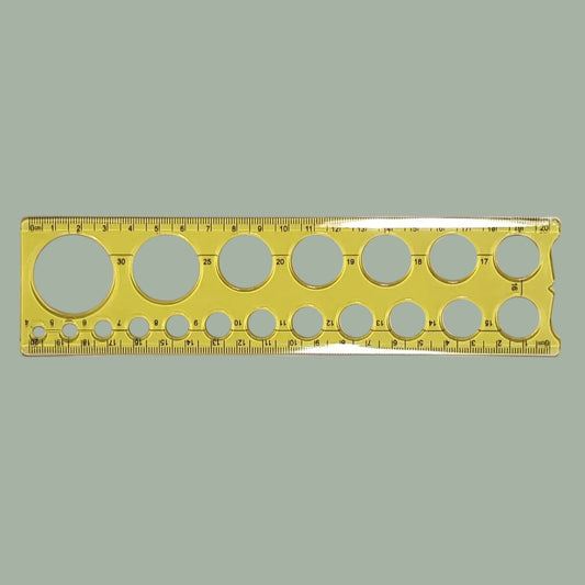 A transparent yellow plastic ruler with multiple circular cutouts of varying sizes and printed measurement markings, shown horizontally on a plain light background.