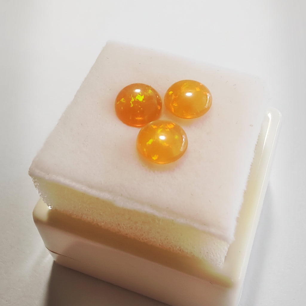 Three fire opals on a white surface.