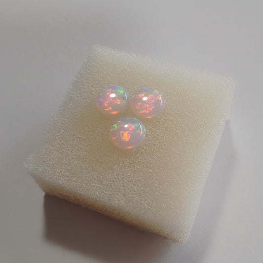 Opal Pink with green fire cabochons on a soft white background