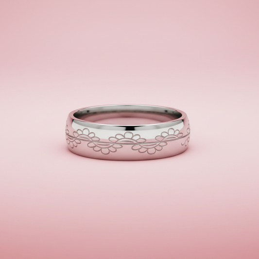 Silver ring with floral engraving on a pink background
