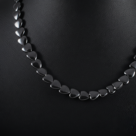 "Close up of flat hematite heart beads 9mm by 8mm showing polished metallic surface and heart shape detail"