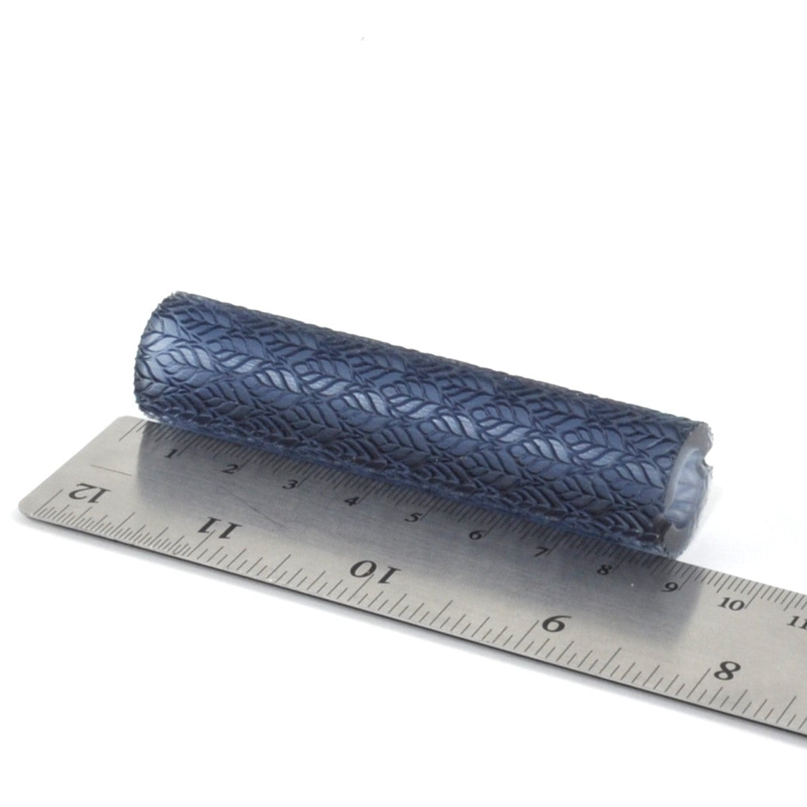 Texture roller with a textured pattern next to a metal ruler on a white background