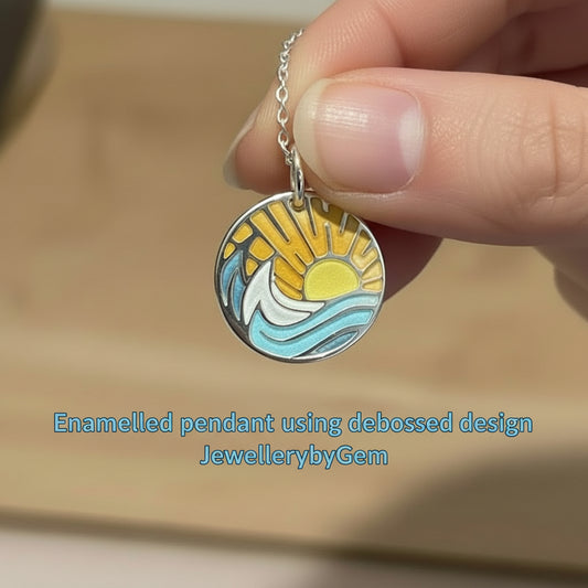 Sun and waves enamelled pendant held by a hand with 'JewellerybyGem' branding.