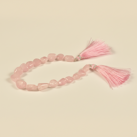 Pink beaded bracelet with tassels on a beige background