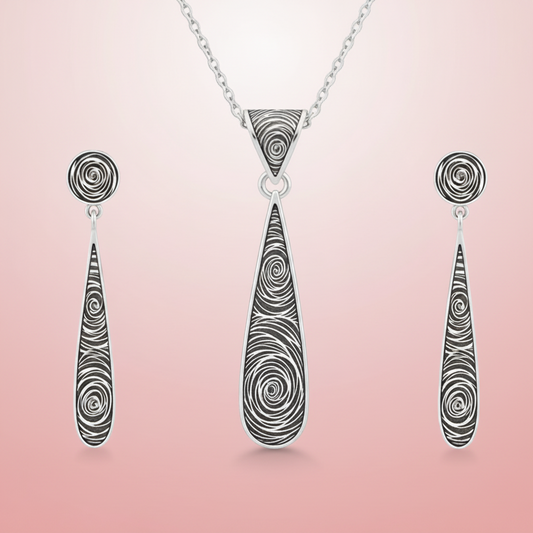 Silver necklace with teardrop-shaped pendant and matching earrings on a pink background