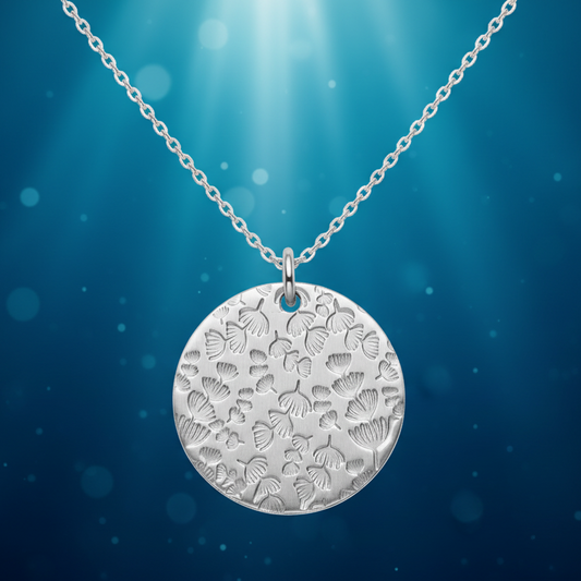 Silver necklace with a round pendant on a blue underwater background