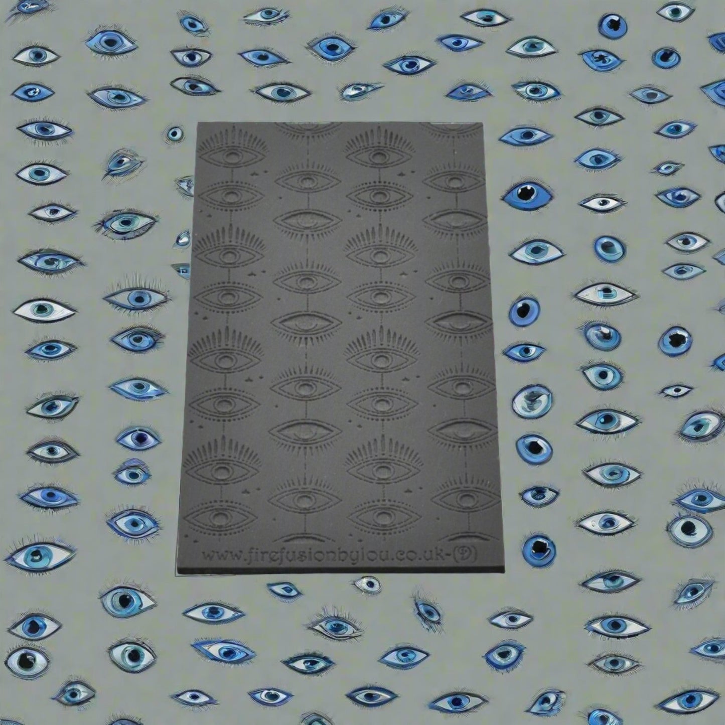 A small vertical mystical eye repeat pattern debossed texture mat in grey material. For use on metal clay or polymer clay.