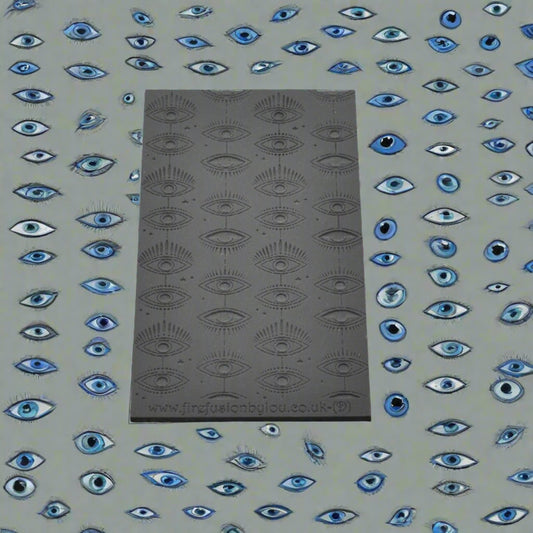 A small vertical mystical eye repeat pattern debossed texture mat in grey material. For use on metal clay or polymer clay.