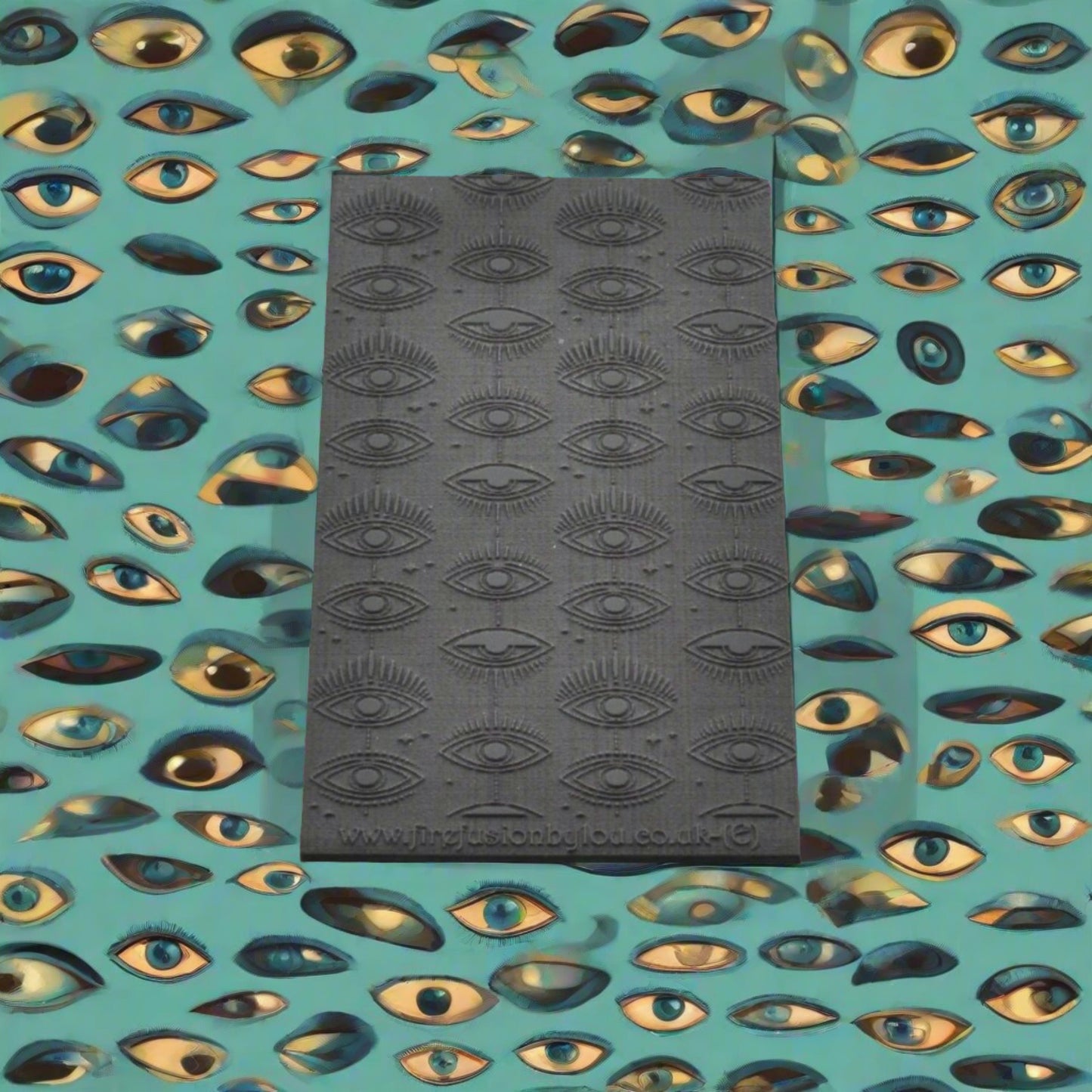 A small vertical mystical eye repeat pattern embossed texture mat in grey material. For use on metal clay or polymer clay.