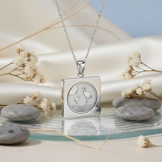 Silver necklace with a pendant featuring a design of two birds on a pebbles and dried flowers background