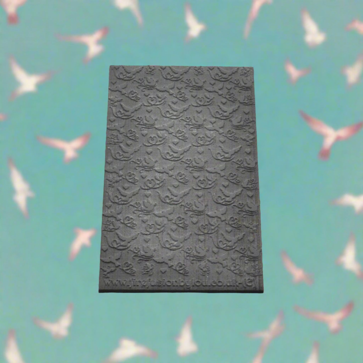 A lovebird pattern embossed texture mat in grey material. This texture mat will give you a debossed effect on metal clay or polymer clay.