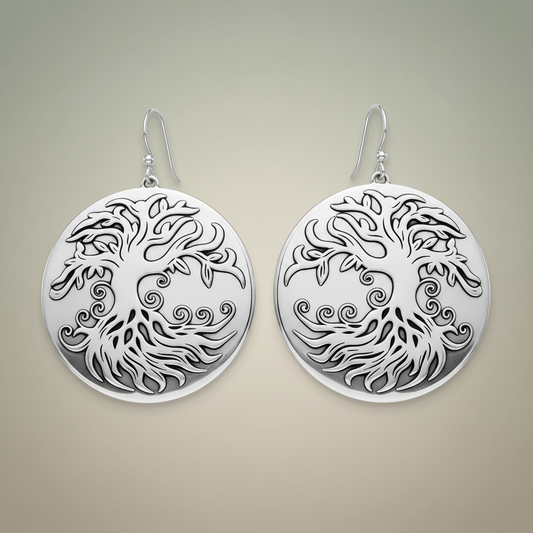 Pair of silver earrings with intricate tree design on a white background