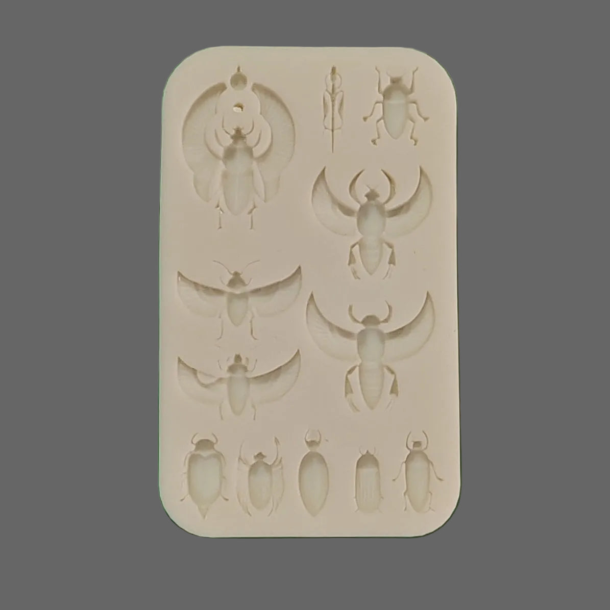 A white silicone mold tray featuring multiple insect-shaped cavities, including a large scarab beetle, and beetles