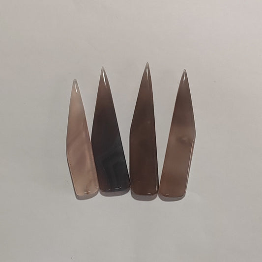 Four pointed agate burnishes pieces in different shades of brown and smoky grey, arranged in a row on a plain light background.