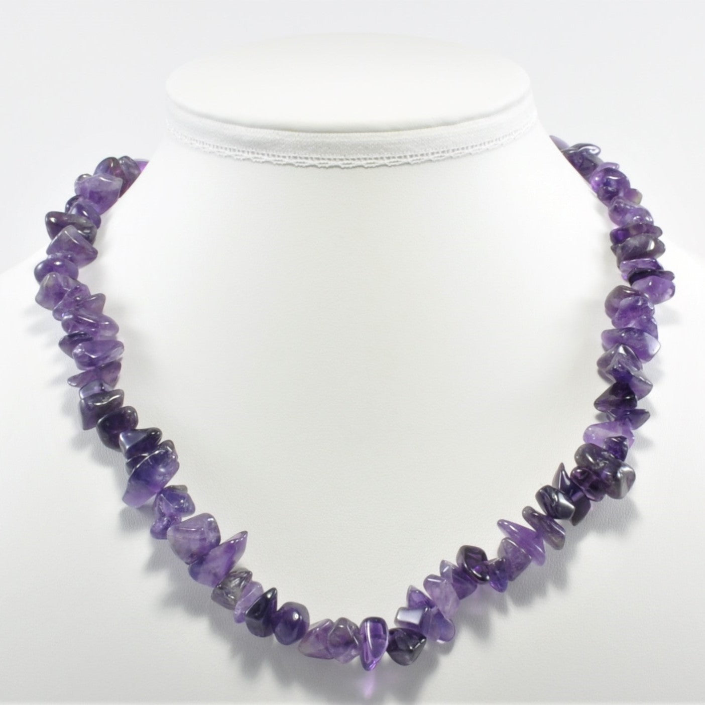 Purple beaded necklace on a mannequin with a white background