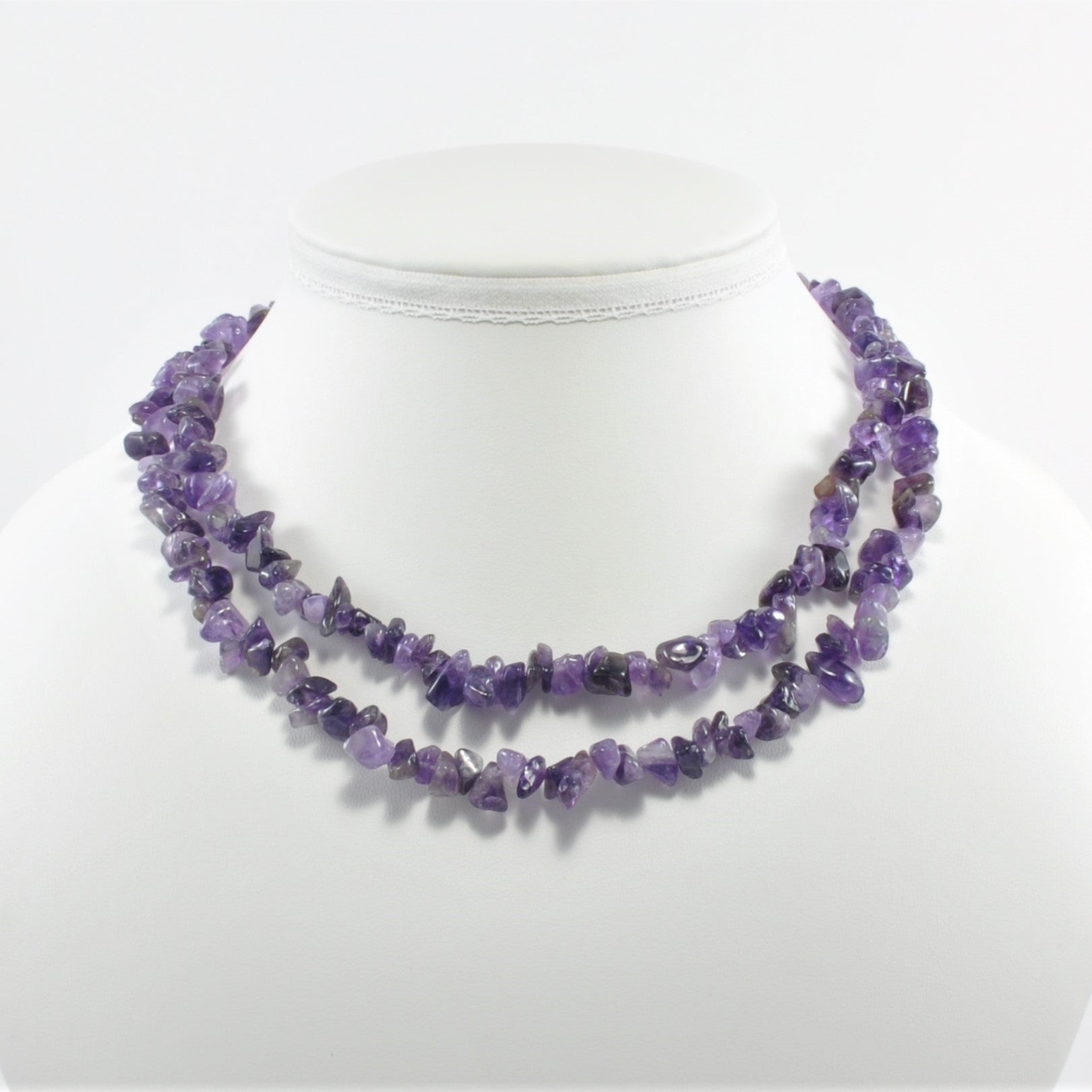 Purple beaded necklace on a mannequin with a white background