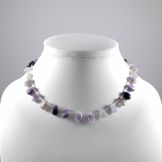 Necklace with purple and white beads on a mannequin against a gray background
