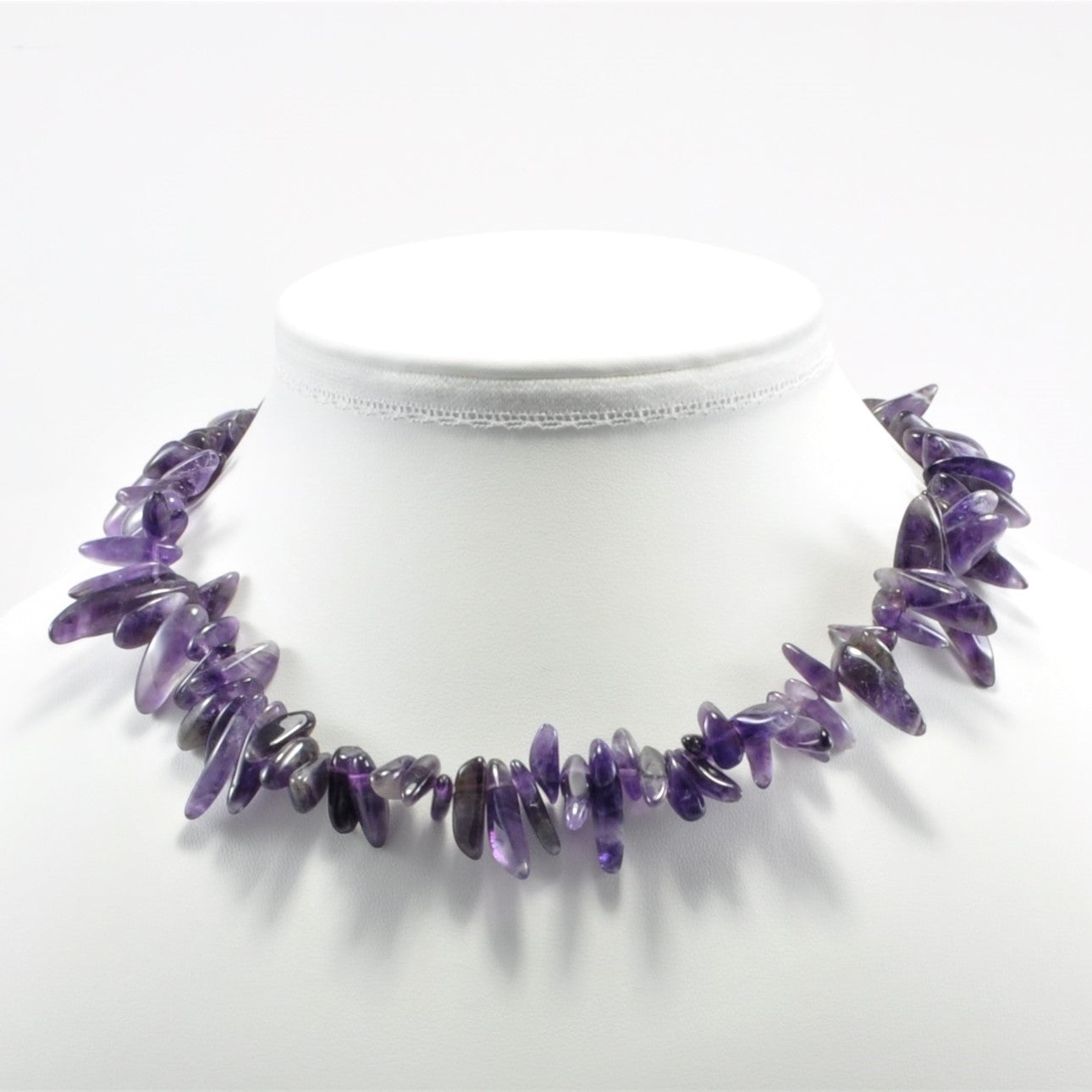 Purple beaded necklace on a mannequin with a white background