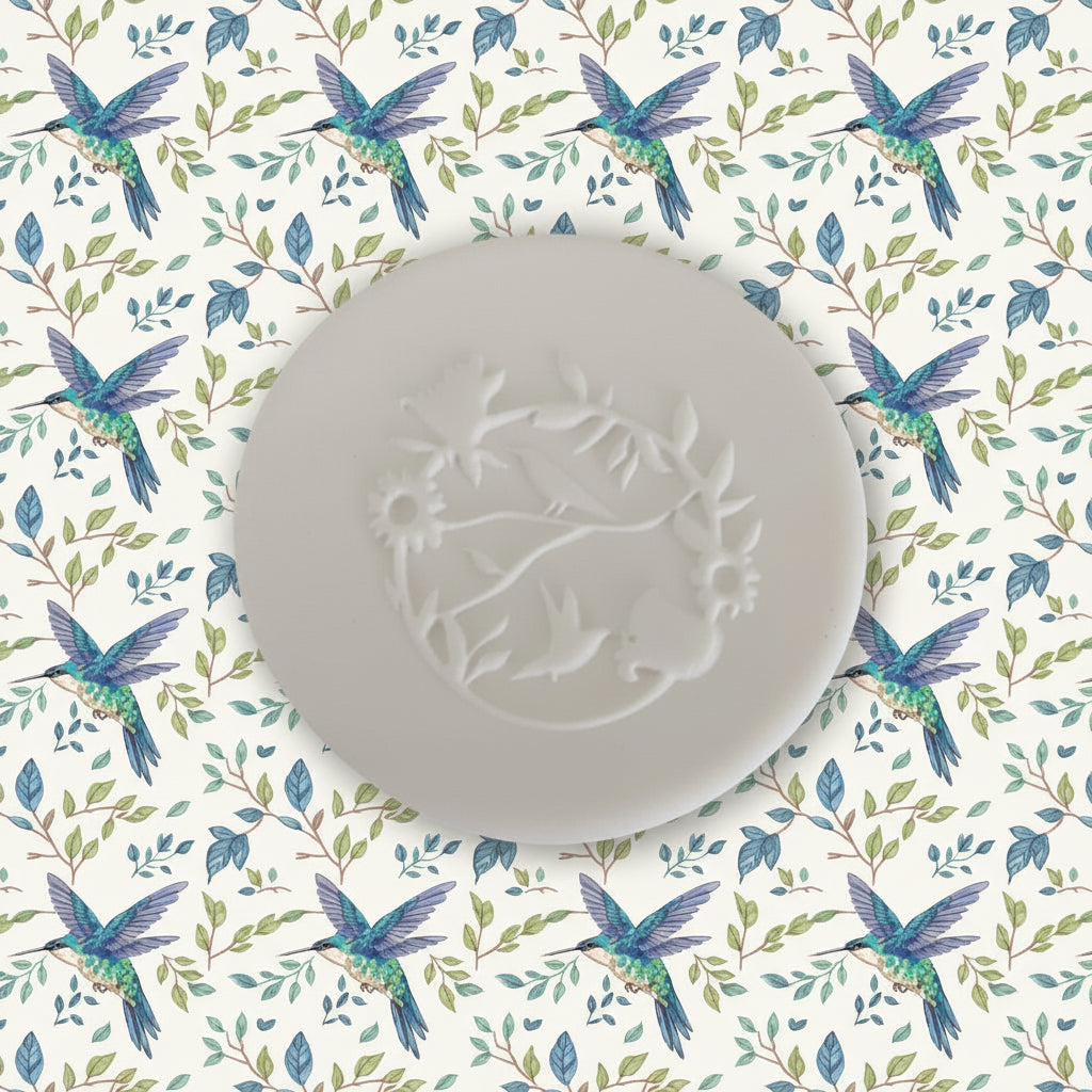 A round clay with an embossed floral and bird design, shown on a plain light gray surface.