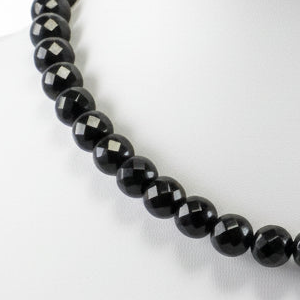 Close-up of a black beaded necklace on a white background