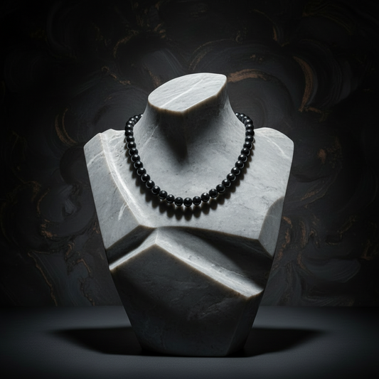 Black beaded necklace on a white marble bust against a dark background