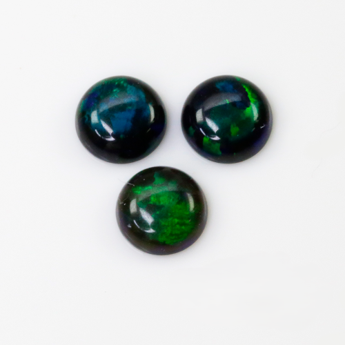 Three round cabochon gemstones with a dark black base and vibrant green and blue iridescent opal flashes, arranged on a plain white background.