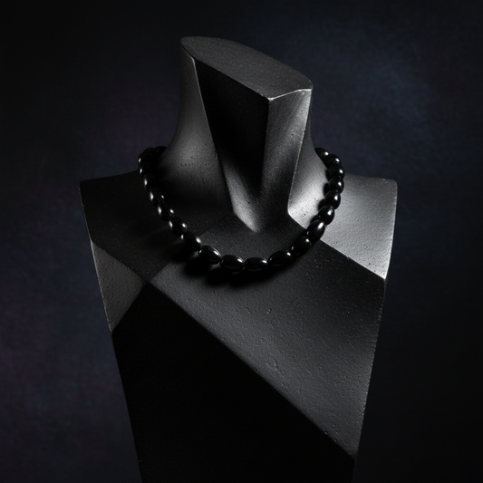 Black beaded necklace on a black mannequin against a dark background