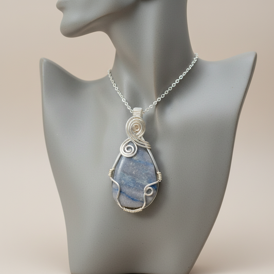 Blue teardrop pendant on a silver chain displayed on a mannequin neck.