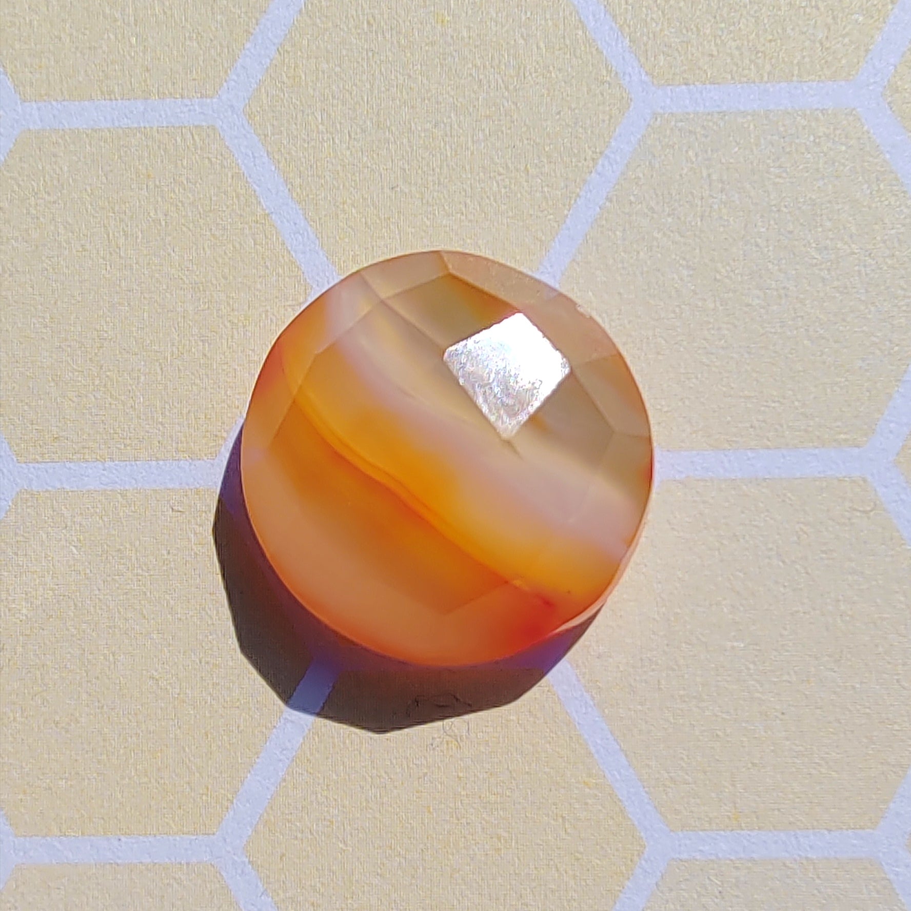 Round orange-brown stone on a beige surface with hexagonal pattern