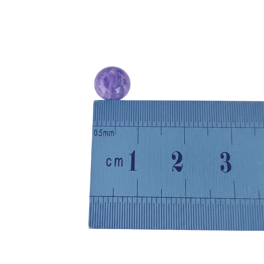 Purple stone next to a ruler on a light purple background