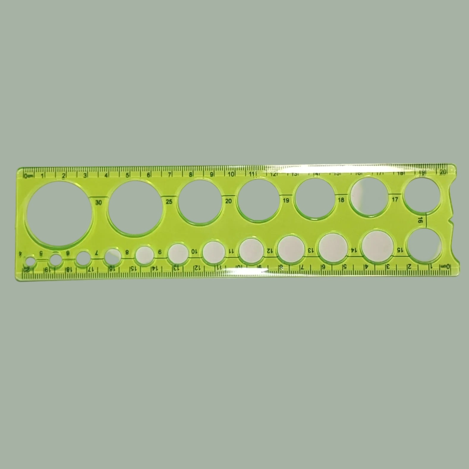 A bright lime green plastic drafting ruler with multiple circular template cutouts and printed measurement markings, shown on a plain light background.