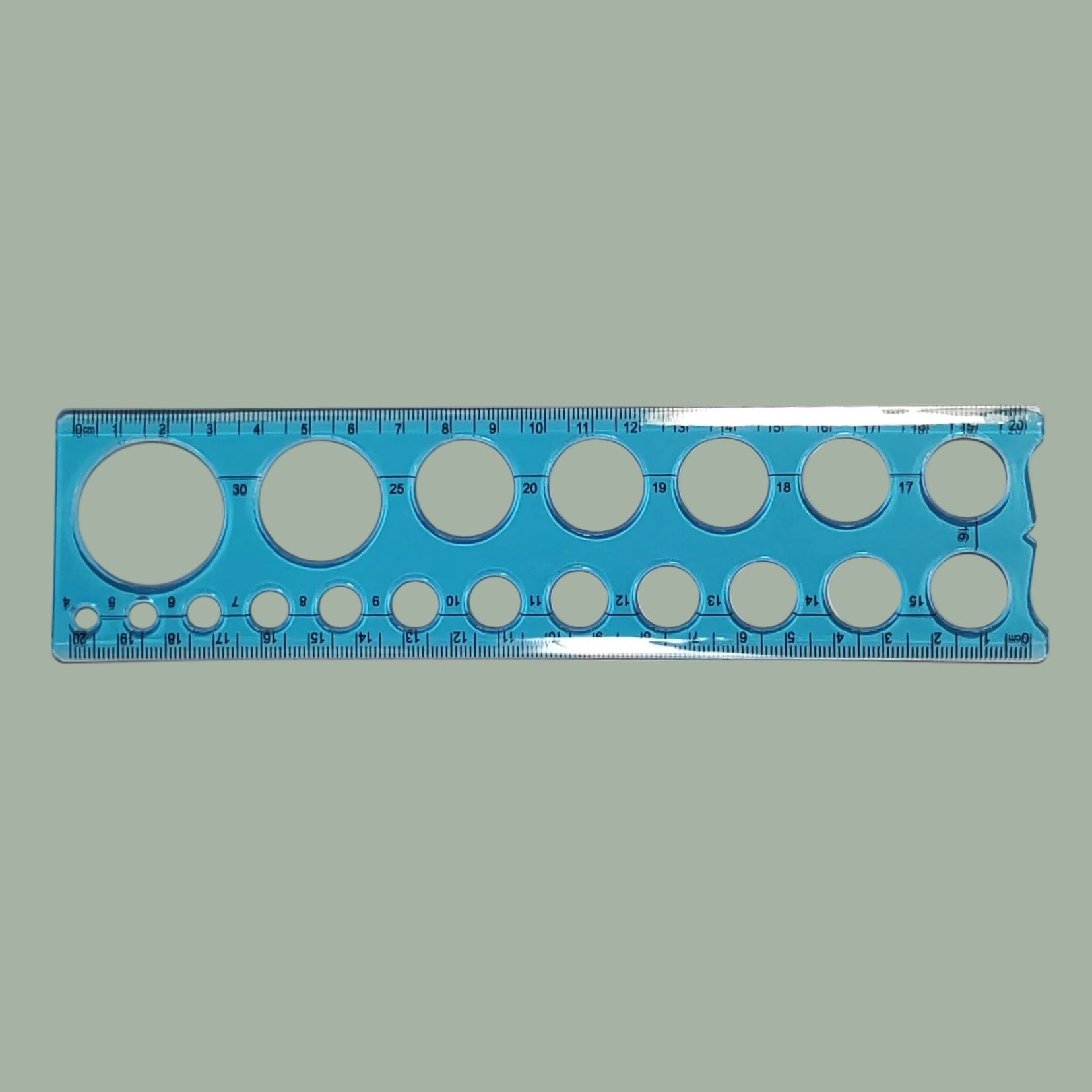 A blue plastic circular template ruler with multiple sizes of circular cutouts and printed measurement markings, shown on a plain light background.