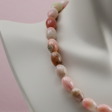 Necklace with pink and brown beads on a mannequin against a pink background