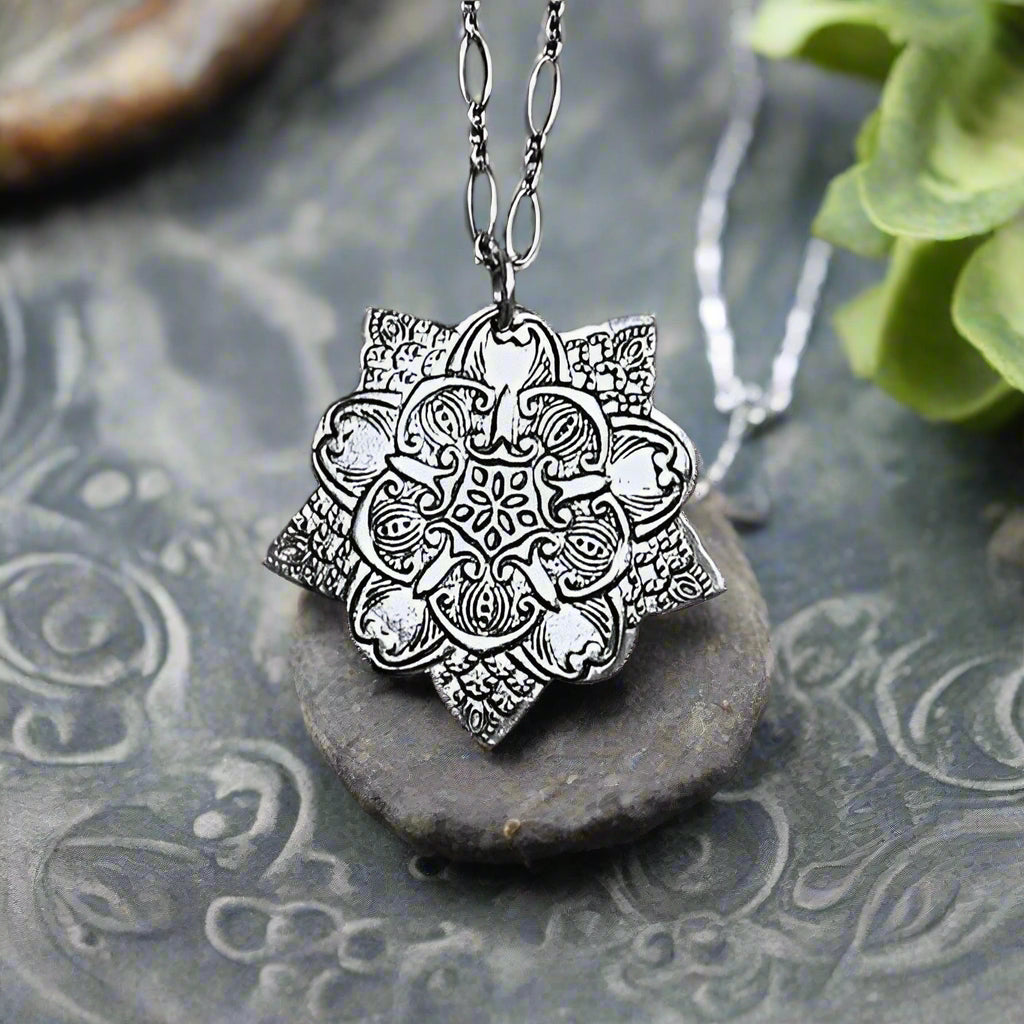 This pendant was made using white bronze metal clay. The impression on the pendant has been made using a mandala times six texture mat, made by firefusionbylou.co.uk