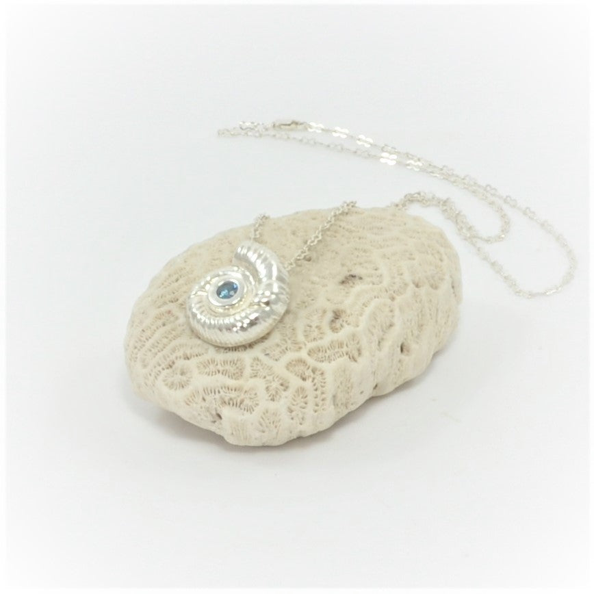 This substantial 999 fine silver fossil pendant features a dual link 925 silver chain, with a sparkling azure cubic zirconia centrepiece. Certified with a full London hallmark on the reverse.    Weight of fossil pendant is 10g  The size of the fossil pendant is 20mm x 18mm  The chain is 20 inches   Total weight of chain and pendant is 13 grams