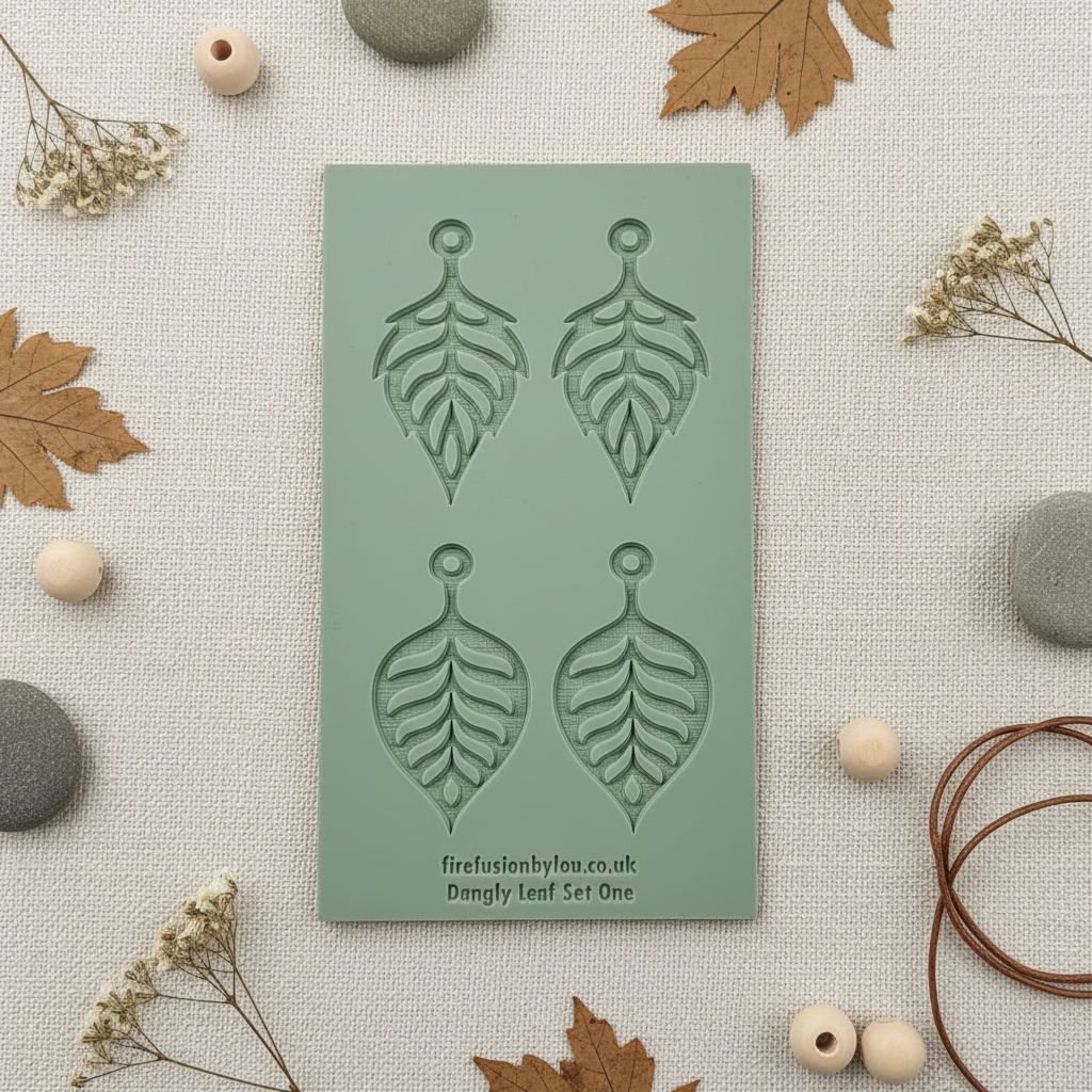 Green rubber with leaf-shaped earrings on a textured surface with leaves and stones.