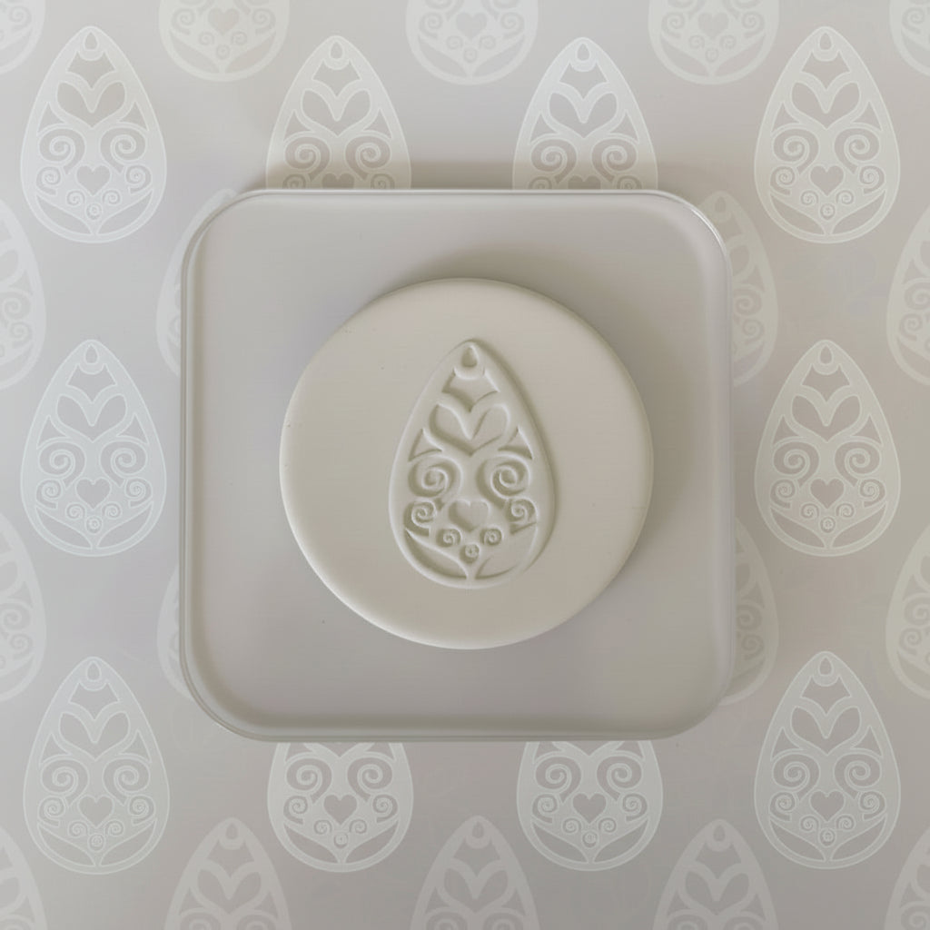 White clay stamped with decorative design on a patterned background.