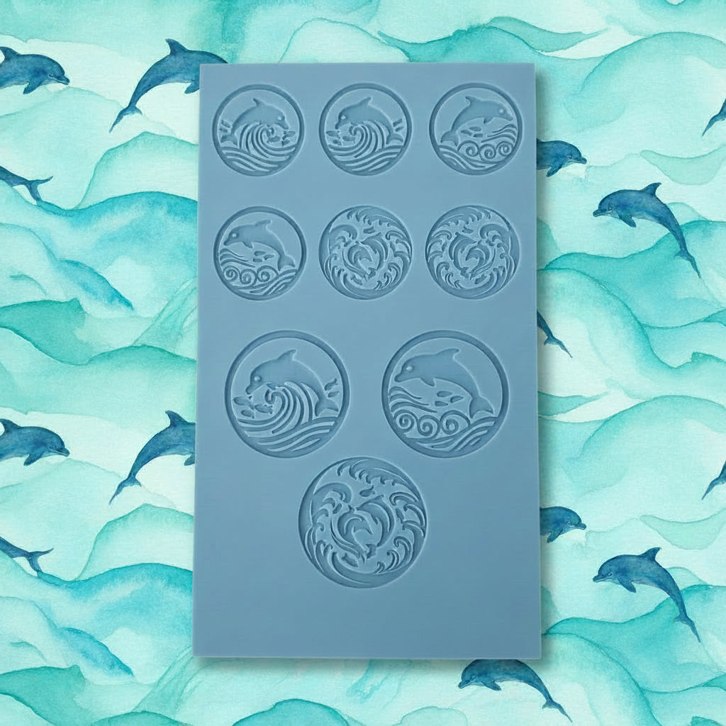 A blue texture tile with nine circular cavities, each featuring an embossed wave and dolphin motif.