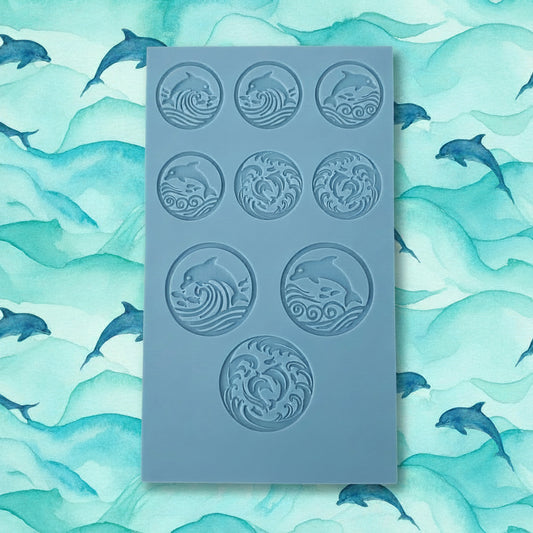 A blue texture tile with nine circular cavities, each featuring an embossed wave and dolphin motif.