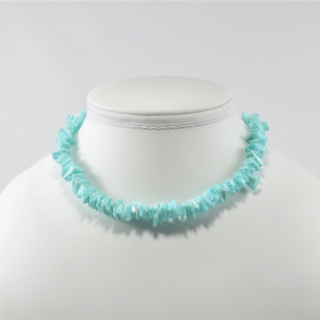 Turquoise necklace on a mannequin bust against a white background