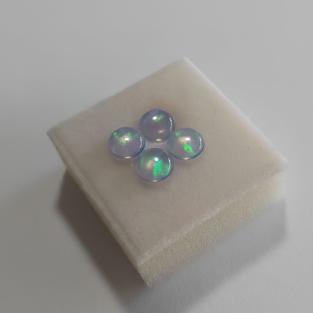Three Blue with green fire  opal stones on a fabric Jewellery square with a plain background
