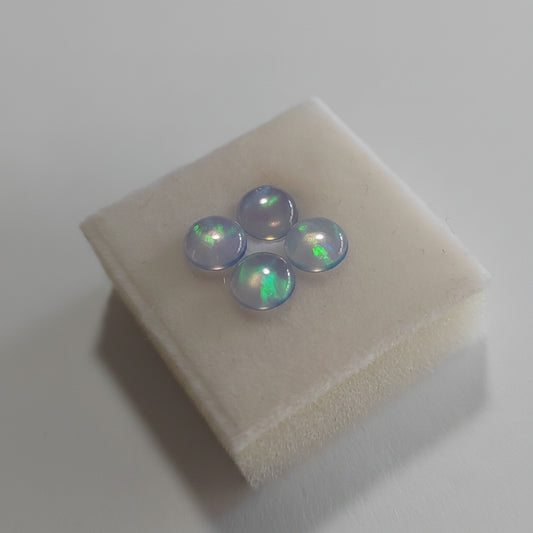 Three Blue with green fire  opal stones on a fabric Jewellery square with a plain background