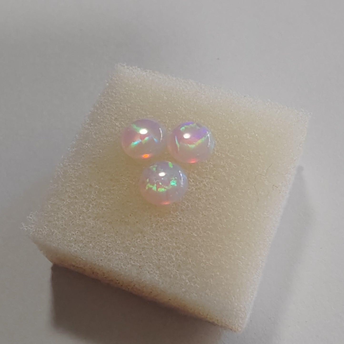 Opal Pink with green fire cabochons on a soft white background