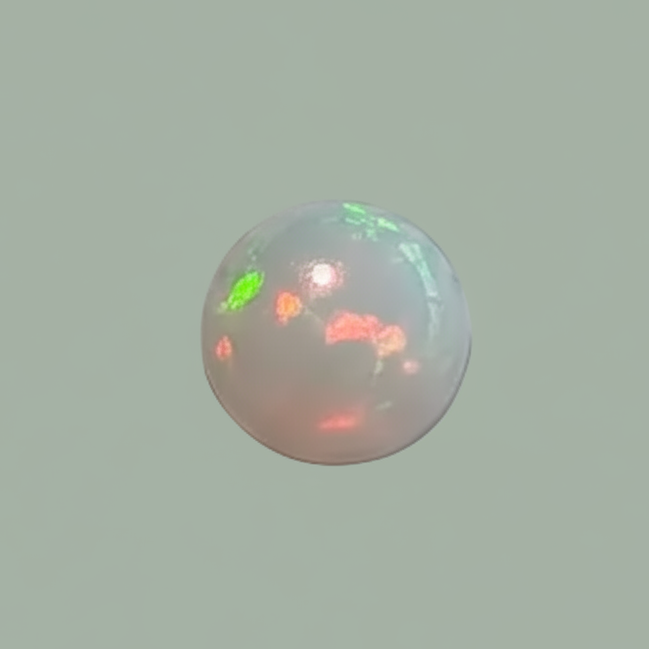 A small spherical opal gemstone with a milky white base and shifting iridescent flashes of green, pink, and orange, centered on a solid sage green background.