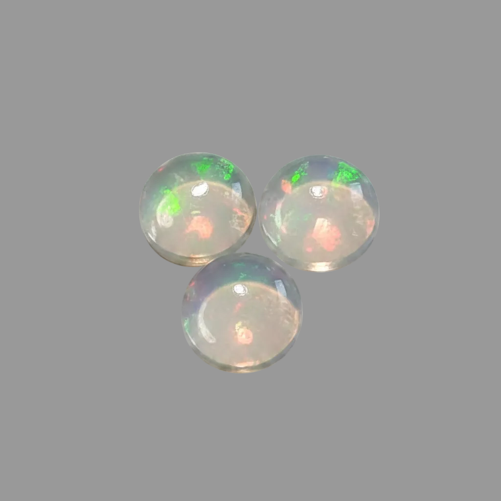 Three round cabochon opal gemstones with iridescent green, orange, flashes, displayed on a solid white background.